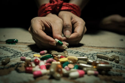 Low section of woman tied with rope having pills in darkroom