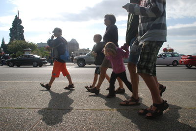 People standing on street in city against sky