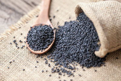 Close-up of black sesame seeds in wooden spoon and sack