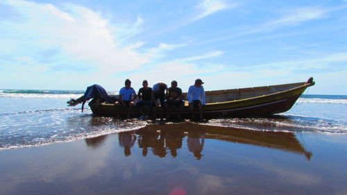 People on boat in sea against sky