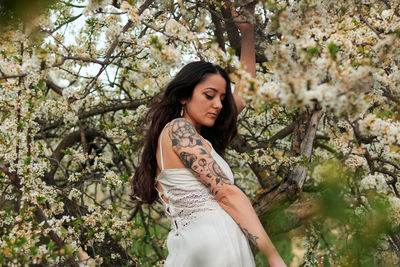 Young woman with pink flower against trees