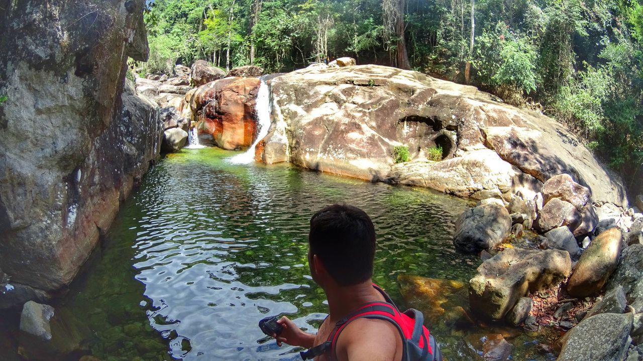 water, lifestyles, low section, leisure activity, person, tree, rock - object, men, stream, river, standing, reflection, nature, day, personal perspective, unrecognizable person