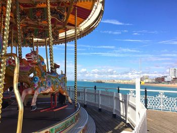 Man at amusement park by sea against sky