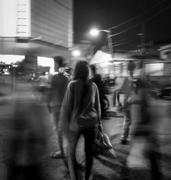 Blurred motion of people walking on road at night