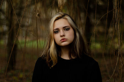 Portrait of beautiful young woman standing against plants outdoors