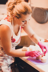 Woman decorating cupcake in kitchen at home