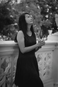 Portrait of young woman standing against trees