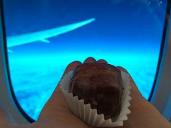 Close-up of hand against blue sky