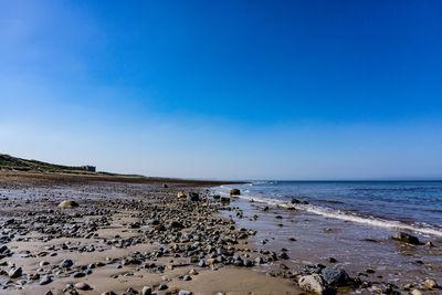 Scenic view of beach against blue sky