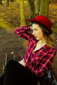 Young woman wearing red hat sitting on park bench