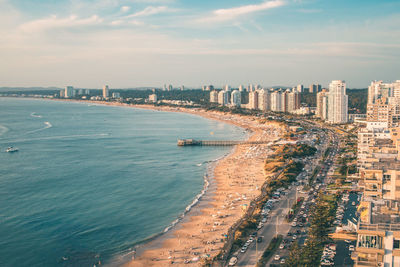 Aerial view of city by sea against sky