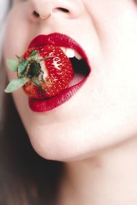 Cropped image of woman with red lipstick eating strawberry