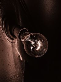 Low angle view of illuminated light bulb against black background
