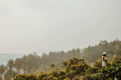 Man standing by tree against sky