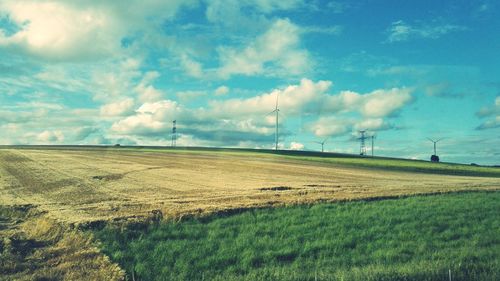 Scenic view of grassy field against cloudy sky