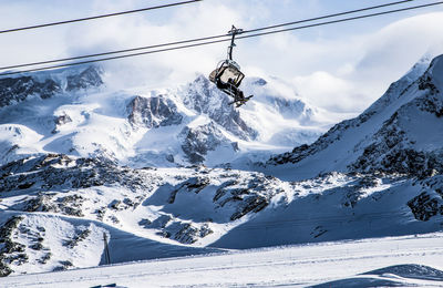 Overhead cable car and snowcapped mountains against sky