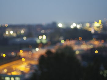 Defocused image of illuminated cityscape against sky at night