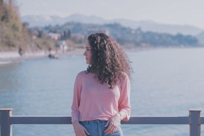 Young woman standing against sky