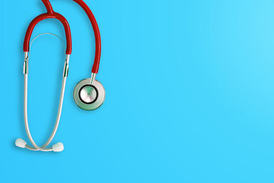 Close-up of light bulb hanging against blue wall