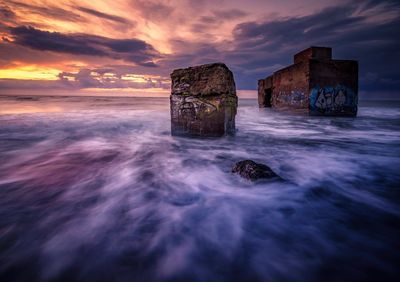 Lifeguard hut on beach against sky during sunset