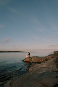Man relaxing in sea against sky during sunset