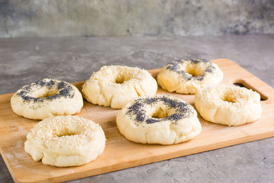 Raw bagels with poppy seeds and sesame seeds on a board on the table. homemade pastries