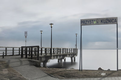 Information sign on street against sky