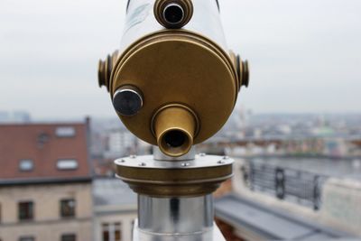 Close-up of coin-operated binoculars against cityscape