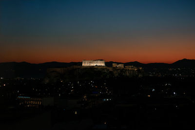 Illuminated cityscape against sky during sunset