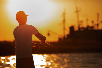 Rear view of man standing against sky during sunset