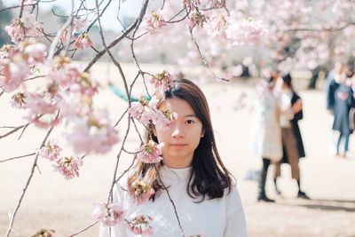 Close-up of young woman with flowers on tree