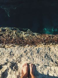 Low section of man standing on cliff at sea