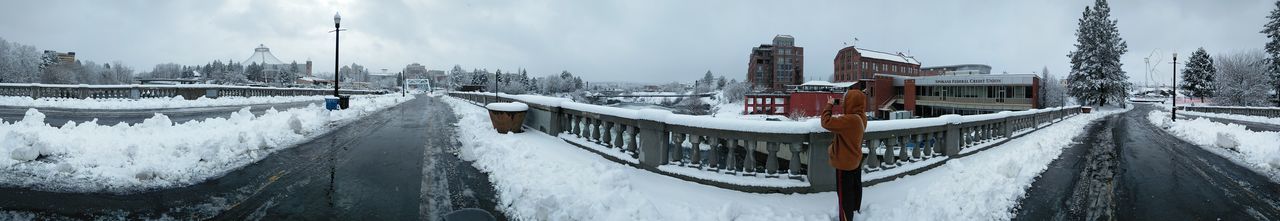 Panoramic view of frozen lake in city against sky