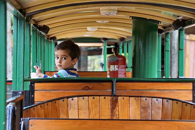 Portrait of boy sitting on seat in train