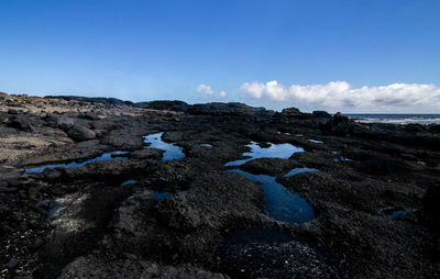 Rocks on land against blue sky