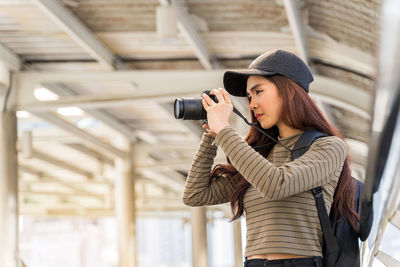 Woman photographing with mobile phone while standing outdoors