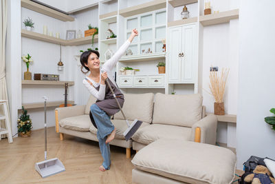 Young woman using mobile phone while sitting on sofa at home