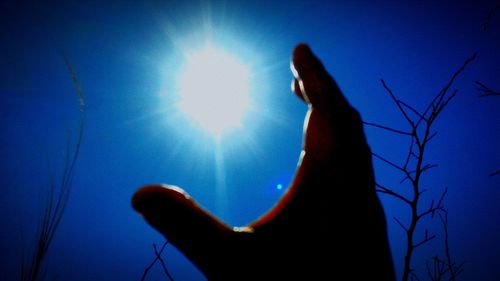 Low angle view of silhouette against blue sky