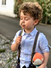 Boy smelling dandelion while standing outdoors