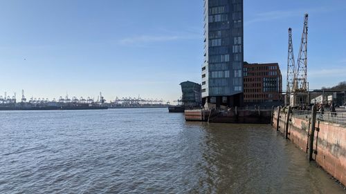 Bridge over river by buildings against sky