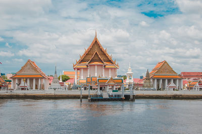 View of building by river against cloudy sky