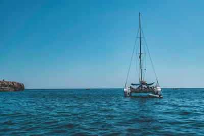 Sailboat sailing in sea against clear sky