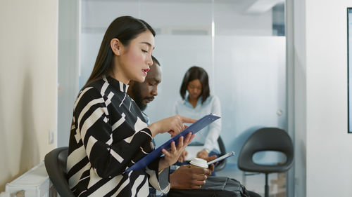 Woman with clipboard sitting on chair in waiting room