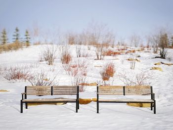 Empty bench on snow covered field during winter