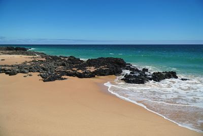 Scenic view of beach against clear blue sky