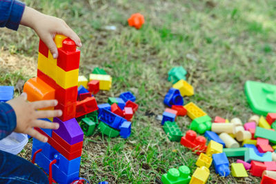 Cropped image of boy playing with toy blocks on grass