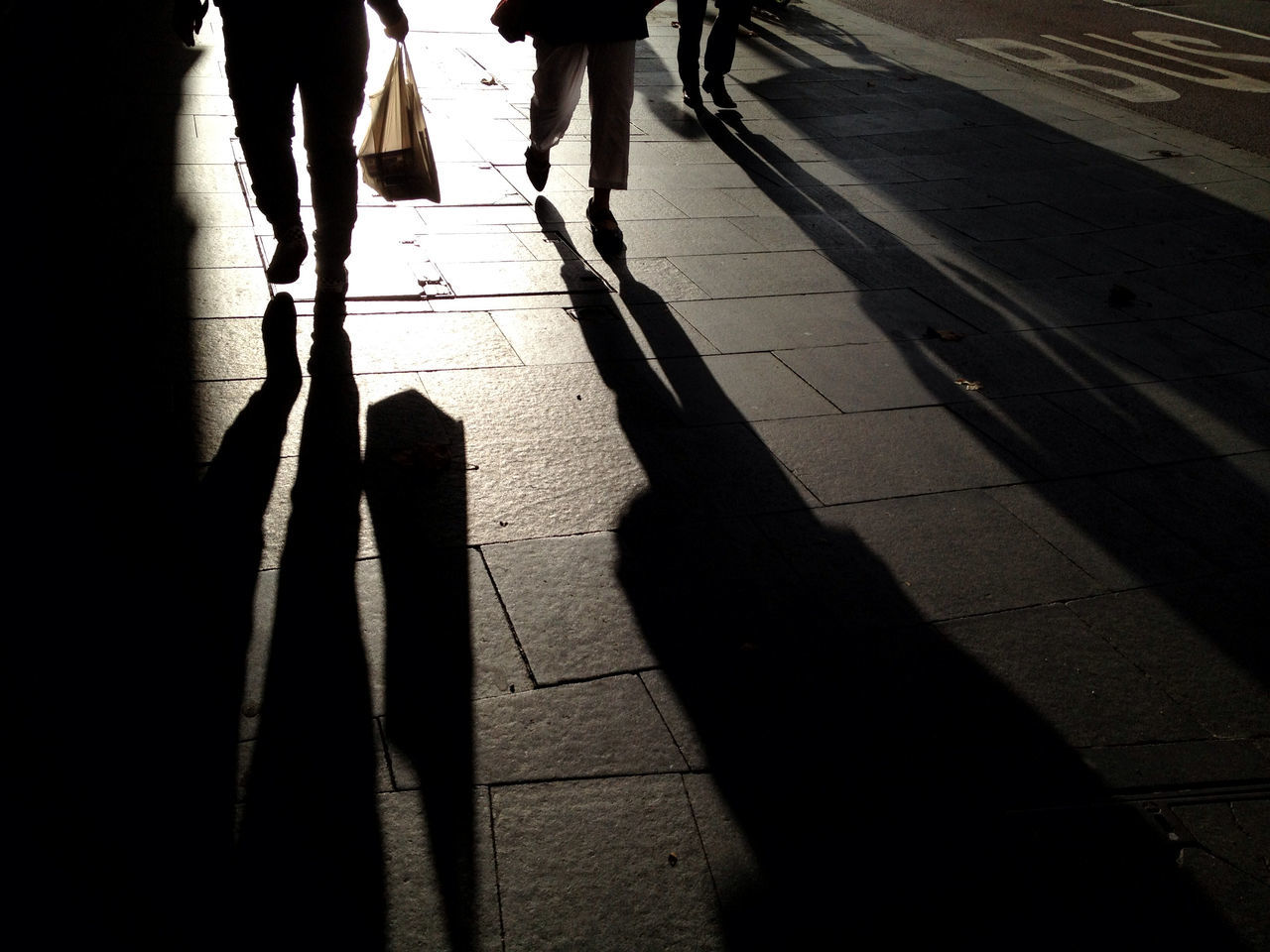 low section, shadow, walking, lifestyles, men, person, togetherness, sunlight, leisure activity, silhouette, standing, street, focus on shadow, bonding, unrecognizable person