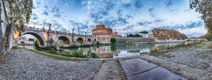 Arch bridge over river against cloudy sky