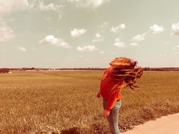 Rear view of woman standing on field against sky