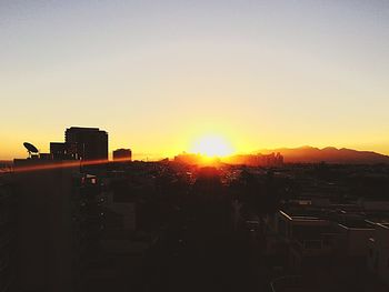 Silhouette of city against sky during sunset